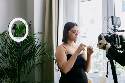 Mulher grava uma avaliação de produto em ambiente interno, usando câmera e iluminação circular.
