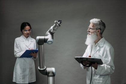 Dois pesquisadores analisam um braço robótico em um laboratório de inovação tecnológica.