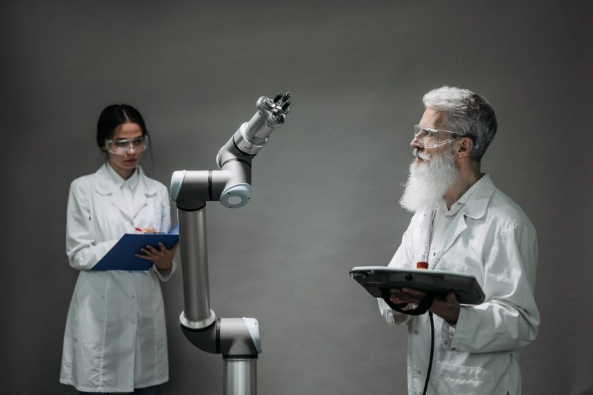 Dois pesquisadores analisam um braço robótico em um laboratório de inovação tecnológica.